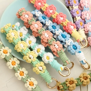 Macro detail of hand-woven daisy flower wrist strap with premium gold metal ring