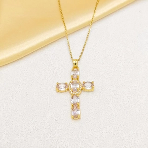 Close-up of gold-plated cross necklace with colorful zircon stones on silk background