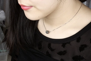 Close-up of S925 silver necklace with a round grey moonstone pendant on a model's neck