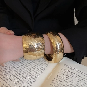 Close-up of gold textured hammer and polished wide bangles on a professional model
