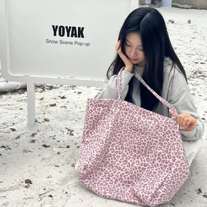 Macro view of pink leopard print suede tote bag with front pocket in a snow scene
