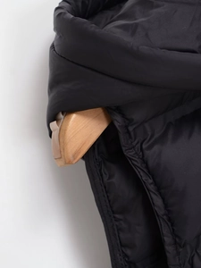 Détail d'un gilet noir matelassé à capuche montrant la texture et les coutures de qualité