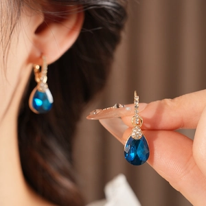 Détail de boucles d'oreilles vintage en or avec pierres bleues en goutte et diamants