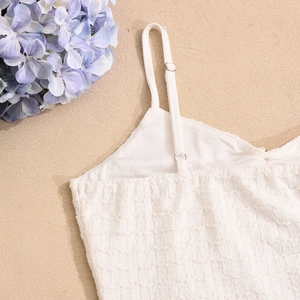 Détail des bretelles réglables et du tissu jacquard 3D texturé d'une robe blanche