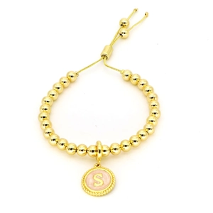 Detail van verstelbare gouden kralenarmband met een roze emaille letter S bedel