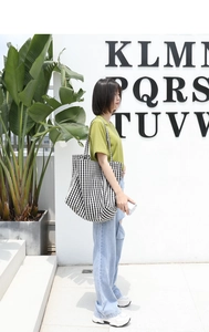 Detail of a large capacity black and white checkered canvas tote bag on a female model