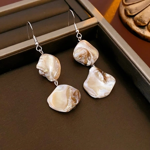 Détail des boucles d'oreilles irrégulières en nacre avec texture naturelle dans un coffret