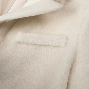Detail of soft cream faux fur texture on the collar and pocket of a cozy winter coat