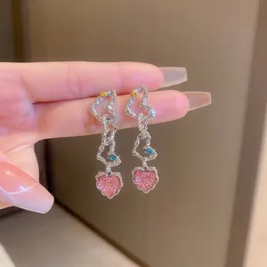 Detailed view of layered silver heart earrings with a glittery pink heart pendant