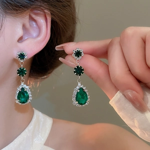 Macro shot of silver vintage earrings with green emerald drop stones and crystals