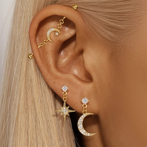Detail of moon and star studs with industrial ear pin in gold finish on ear