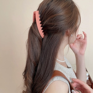 Pince à cheveux en acrylique rose mat présentée sur un modèle coiffé à moitié