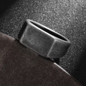 Detailed close-up of vintage industrial signet ring with worn texture and dark grey finish