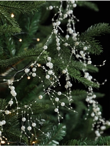 Detail of white artificial pearl garland strands hanging on a green Christmas tree branch