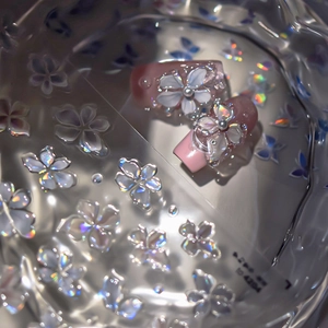 Detailed view of 3D aurora flower nail stickers with pearls in translucent glass bowl