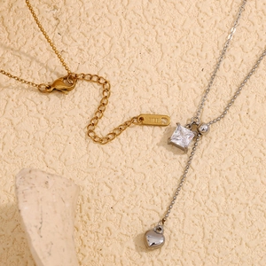 Detail of 18K gold and silver Y-necklace featuring square zircon and heart pendants