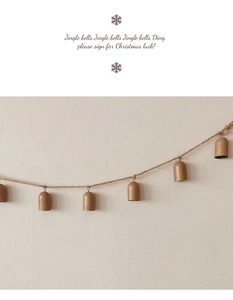 Detail of vintage bronze Christmas bells on twine rope against a minimalist wall
