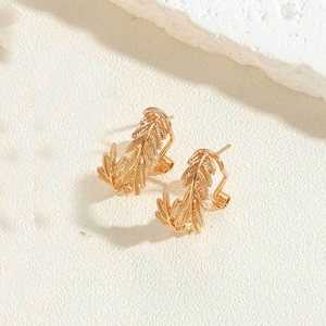 Close-up of 14K gold plated leaf earrings on a minimalist textured background