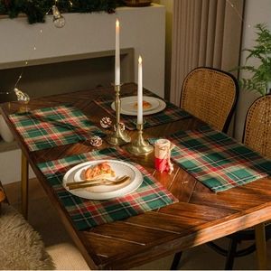 Classic red and green plaid Christmas placemats set on a rustic dark wooden dining table