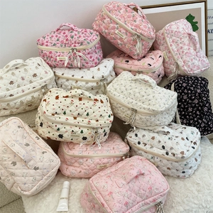 Close-up of quilted makeup bags with floral and cartoon patterns on soft plush surface