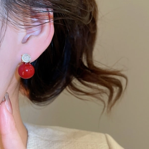 Close-up of elegant red pearl drop earrings with sparkling zircon bow detail on model