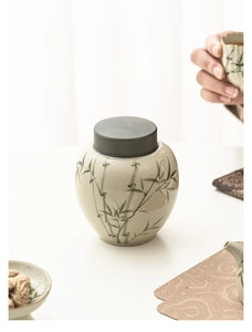Detail of a beige ceramic tea canister with bamboo patterns and elegant metal lid