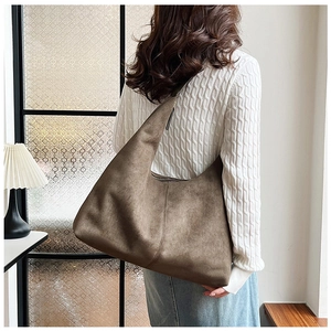 Detailed view of large brown suede tote bag styled with a white cable knit sweater