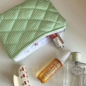 Detail of green plaid quilted makeup bag featuring fresh red cherry pattern lining