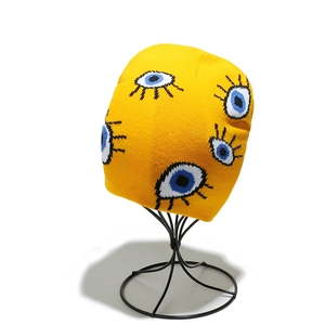 Close-up of bright yellow beanie featuring blue eye jacquard knit patterns and texture