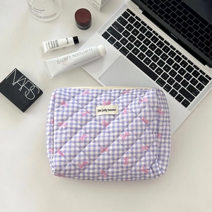 Detail of purple checkered quilted cosmetic bag with pink bows on a desk