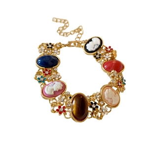 Vintage style gold bracelet featuring embossed portraits and colorful gemstone charms