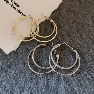 Detail of layered gold and silver hoop earrings featuring textured and smooth metal bands
