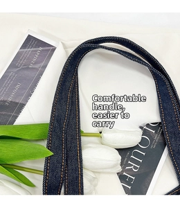 Dettaglio della borsa in denim blu scuro con cuciture gialle e manici molto resistenti