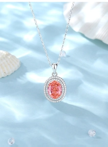 Detailed close-up of pink oval gemstone necklace on ripple silk and shell background