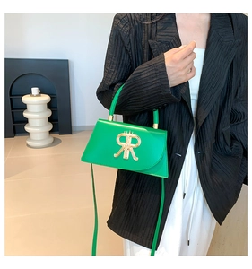 Detailed view of a green leather handbag with a golden RR metal buckle and shoulder strap