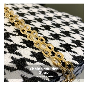Detail of elegant gold chain strap and classic black and white houndstooth fabric texture