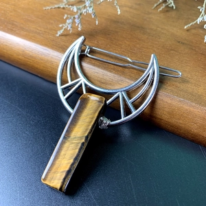 Detailed close-up of a crescent moon hair clip featuring a natural tiger eye stone inlay
