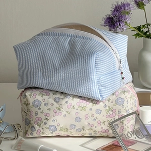 Detail of floral and striped cosmetic bags with cherry charms and soft fabric texture