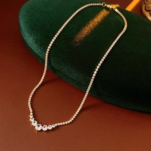 Detailed view of elegant gold-tone zirconia necklace on premium green velvet display stand