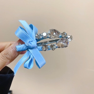 Détail d'une pince à cheveux avec nœud en satin bleu et strass sur base en alliage