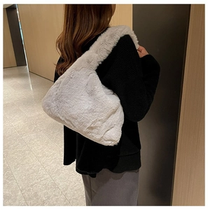Back view of a light gray plush shoulder bag with fluffy faux fur on a model in a cozy hall