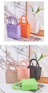Various colorful PVC jelly bags with rivet details displayed in a cozy home setting