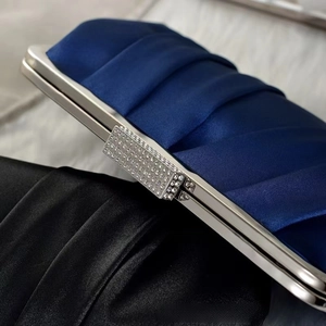 Detailed view of elegant satin evening bag with pleated texture and crystal clasp