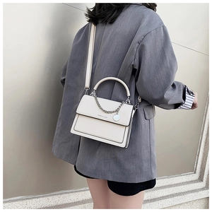 Detail of off-white crossbody bag with metal chain and elegant minimalist flap design