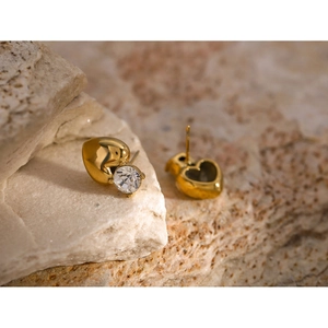 Macro detail of 18k gold heart stud earring with clear crystal on natural stone