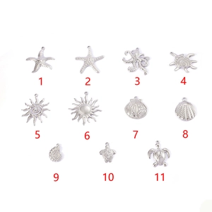 Collection of 11 silver ocean-themed pendants including starfish and sea turtles on white