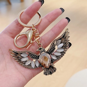 Golden eagle wings keychain with amber teardrop gemstone and grey cat-eye stones