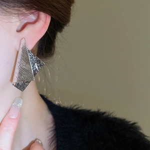 Close-up of irregular silver geometric folding earrings on model for a modern look