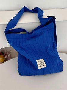 Minimalist blue quilted canvas tote bag with vertical stripes and adjustable shoulder strap