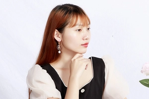 Detail of gold hollow figure earrings with white pearl drop on female model